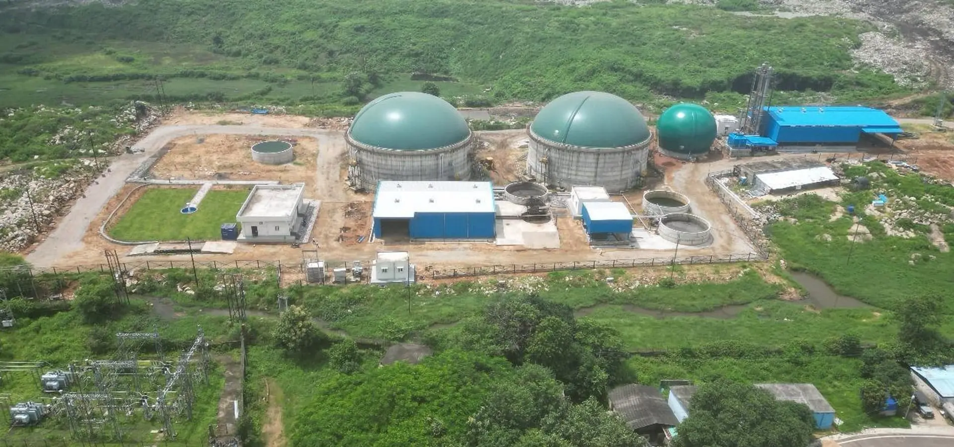 Aerial view of a compressed biogas plant with green digester domes and a treatment area