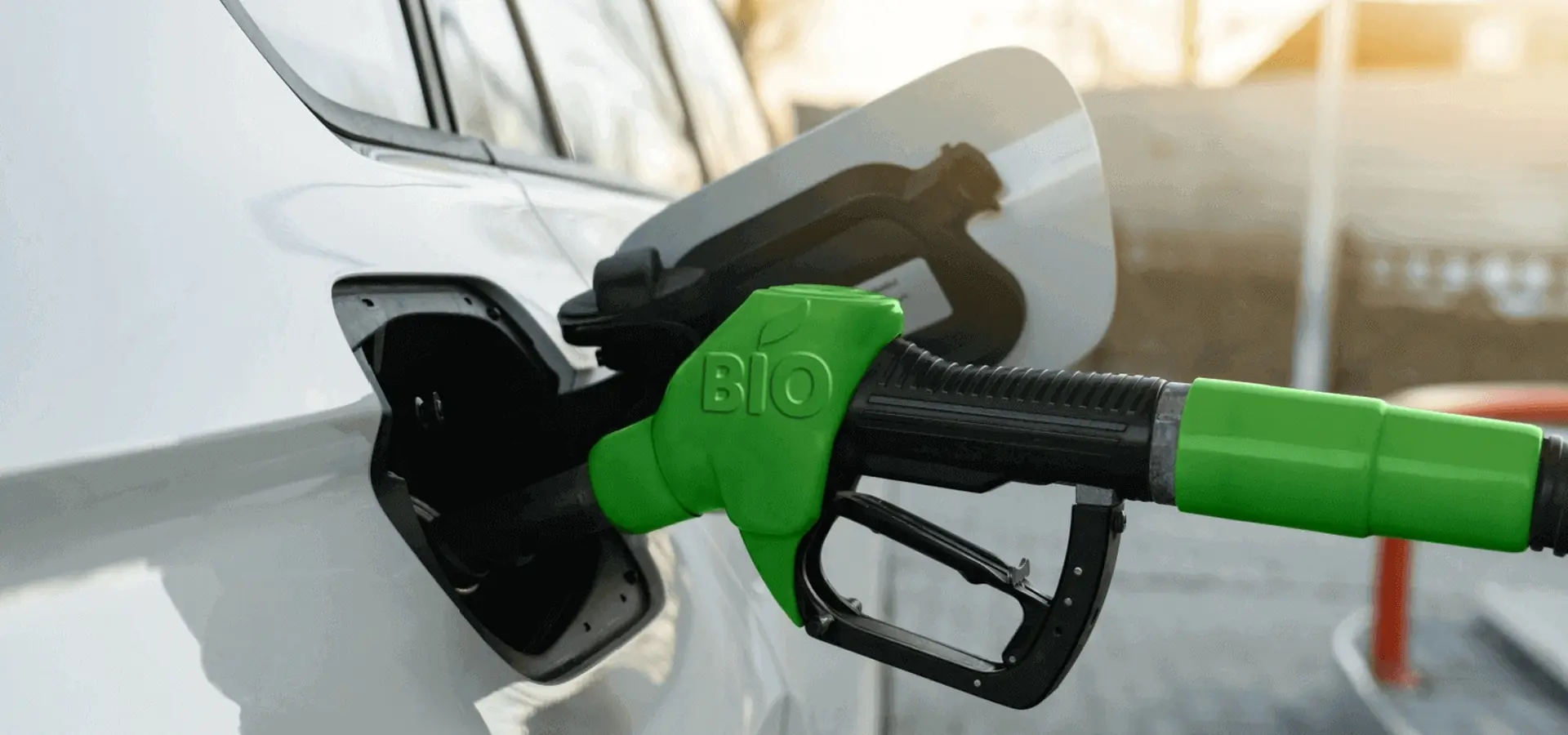 Green BIO fuel nozzle refuelling a white car