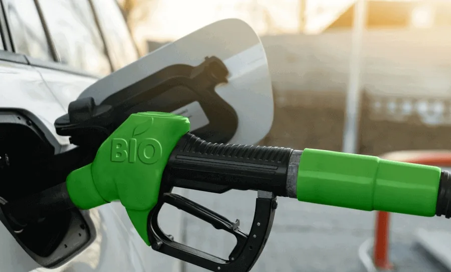 Green bio fuel nozzle refuelling a white car