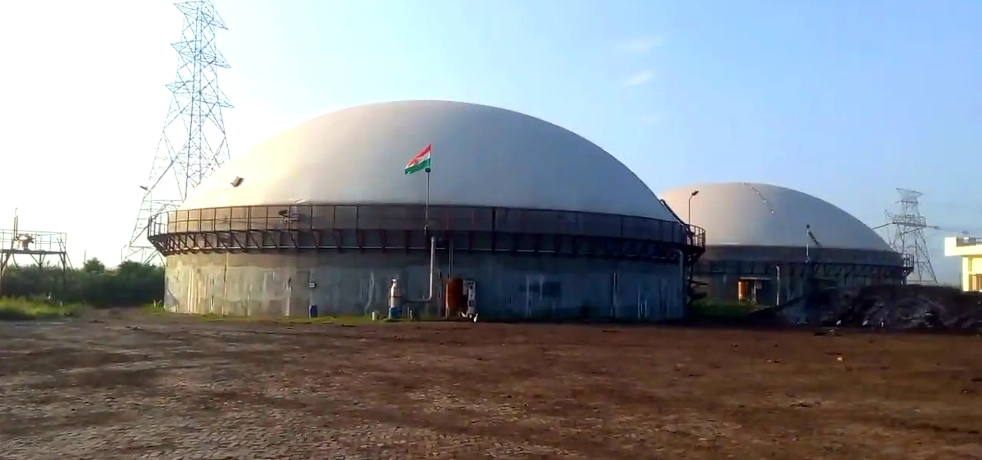 Biogas holder dome with the Indian flag flying above it at dawn